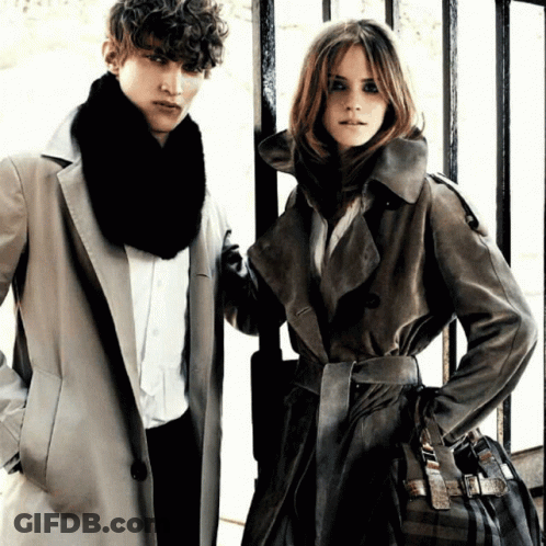 A Man And A Woman Are Standing Next To Each Other Wearing Coats GIF