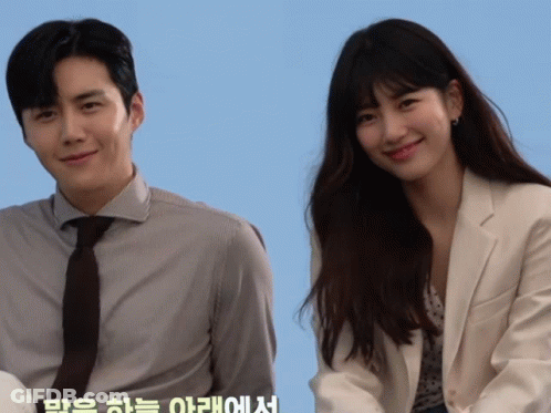 A Man And A Woman Are Standing Next To Each Other With A Blue Background GIF