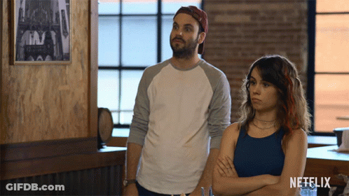Man And Woman Standing Next To Netflix Logo GIF