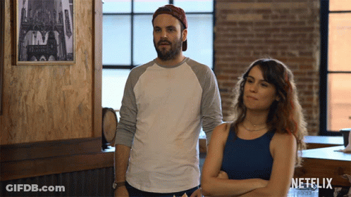 Man And Woman Standing Next To Netflix Logo GIF