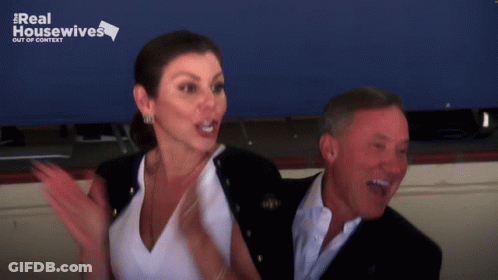A Man And A Woman Are Standing Next To Each Other With A Real Housewives Logo Behind Them GIF