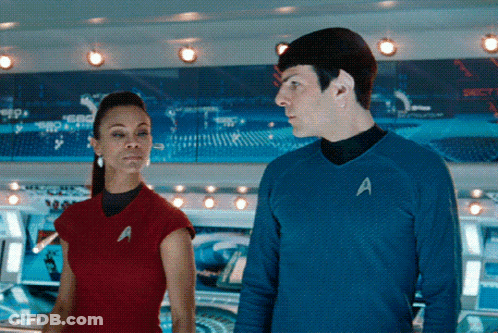 A Man And A Woman Are Standing Next To Each Other With The Man Wearing A Blue Shirt With The Letter A On It GIF