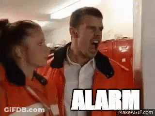A Man And A Woman Are Standing Next To Each Other With The Word Alarm On The Bottom GIF