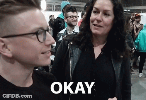 A Man And A Woman Are Standing Next To Each Other With The Word Okay On The Bottom Right GIF