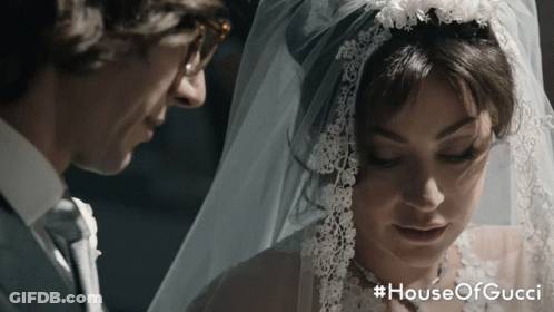 A Man And A Woman Are Standing Next To Each Other With The Words House Of Gucci On The Bottom GIF