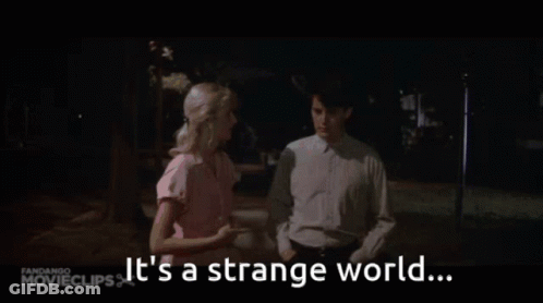 A Man And A Woman Are Standing Next To Each Other With The Words It 'S A Strange World GIF