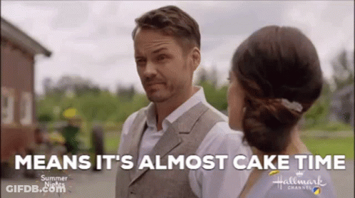 A Man And A Woman Are Standing Next To Each Other With The Words `` Means It 'S Almost Cake Time '' GIF