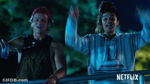 A Man And A Woman Are Standing Next To Each Other With Their Arms In The Air And The Word Netflix Is On The Bottom GIF