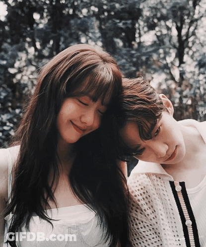 A Man And A Woman Are Standing Next To Each Other With Their Heads On Each Other 'S Shoulders GIF