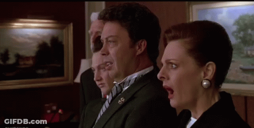 A Man And A Woman Are Standing Next To Each Other With Their Mouths Open In A Room . GIF