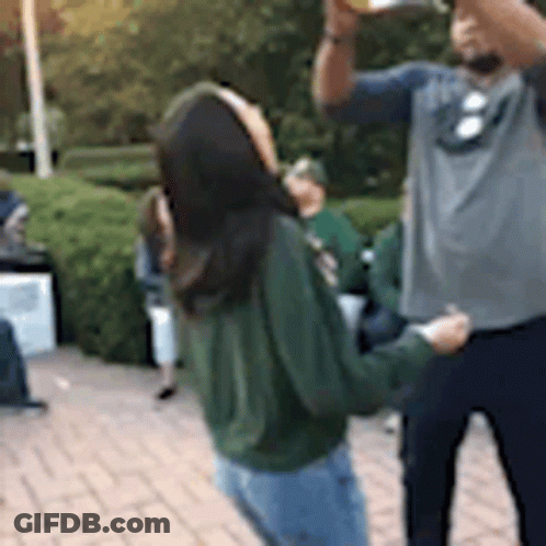A Man And A Woman Are Standing On A Brick Sidewalk . GIF