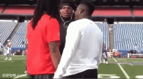 A Man And A Woman Are Standing On A Football Field . GIF
