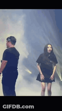 A Man And A Woman Are Standing On A Stage In Front Of A Crowd . GIF