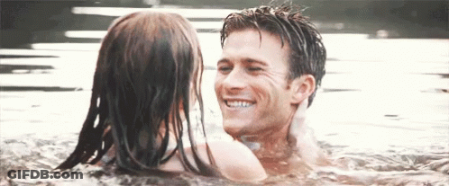 A Man And A Woman Are Swimming In The Water And Smiling At Each Other GIF