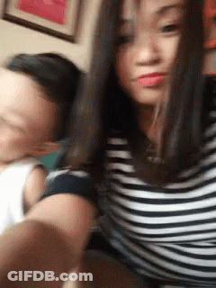 A Man And A Woman Are Taking A Selfie Together . The Woman Is Wearing A Striped Shirt . GIF