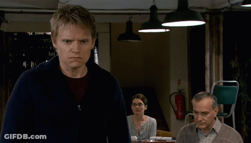 A Man And A Woman Are Talking In Front Of A Door That Has The Word Odds On It GIF
