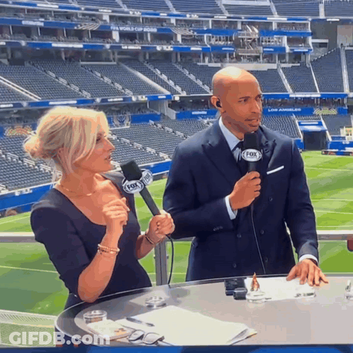 A Man And A Woman Are Talking Into Microphones That Say Fox On Them GIF
