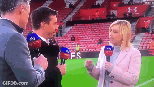 A Man And A Woman Are Talking On A Soccer Field With Microphones That Say Sky Sports On Them GIF