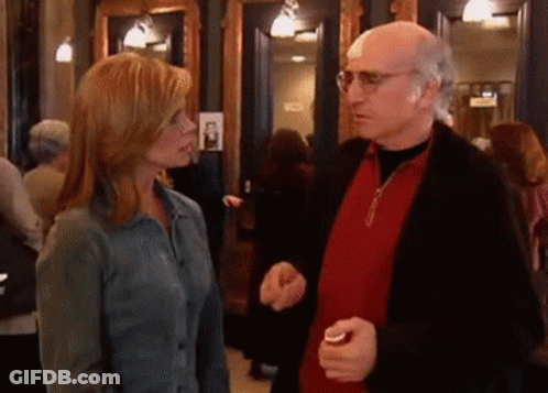 A Man And A Woman Are Talking To Each Other In A Crowded Room GIF