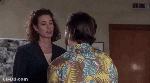 A Man And A Woman Are Talking To Each Other In A Room . The Man Is Wearing A Hawaiian Shirt . GIF