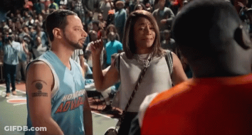 A Man And A Woman Are Talking To Each Other On A Basketball Court . GIF