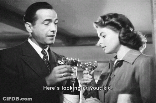 A Man And A Woman Are Toasting With Wine Glasses . The Man Is Holding A Bottle Of Wine . GIF