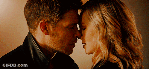 A Man And A Woman Are Touching Their Foreheads GIF
