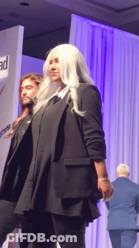 A Man And A Woman Are Walking Down A Runway At A Fashion Show GIF