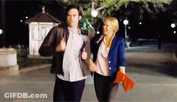 A Man And A Woman Are Walking Down The Street At Night Holding Hands GIF