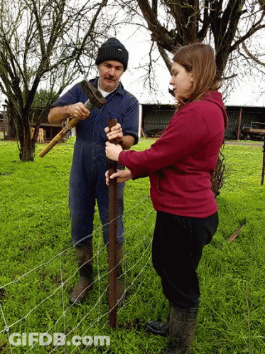 A Man And A Woman Are Working On A Fence Post GIF