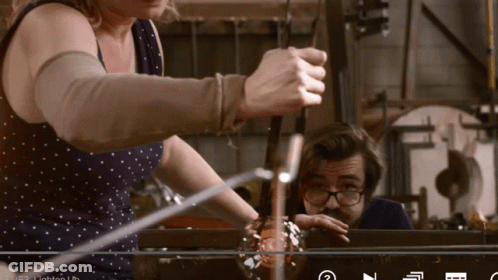 A Man And A Woman Are Working On A Glass Sculpture GIF