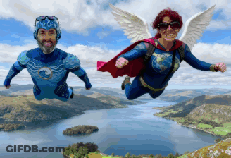A Man And A Woman Flying Over A Body Of Water GIF