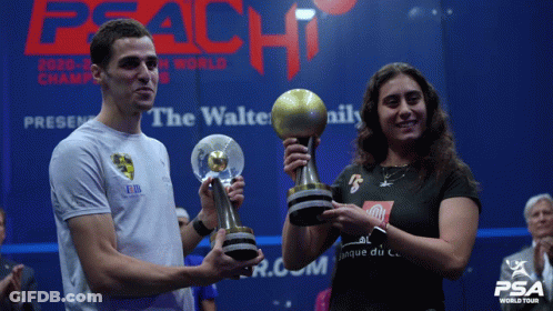 A Man And A Woman Holding Trophies In Front Of A Peach World Tour Sign GIF