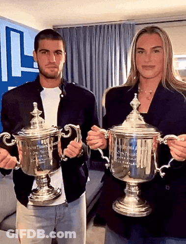 A Man And A Woman Holding Trophies That Say Us Open On Them GIF