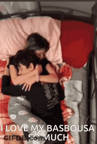 A Man And A Woman Hugging In Bed With The Words I Love My Basbousa So Much GIF