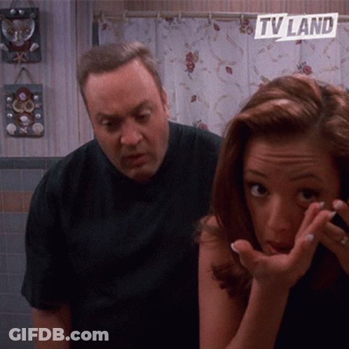 A Man And A Woman In A Bathroom With A Tv Land Sign On The Wall GIF