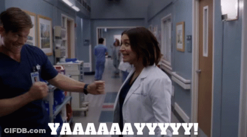 A Man And A Woman In A Hospital Hallway With The Words Yaaaa Aay Yy Yy GIF