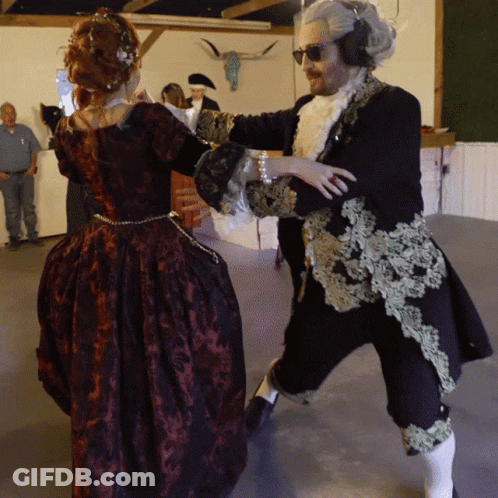 A Man And A Woman In Costume Are Dancing Together GIF
