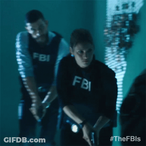 A Man And A Woman In Fbi Uniforms Are Standing In A Dark Room GIF