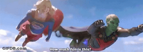 A Man And A Woman In Superhero Costumes Are Flying In The Air . GIF