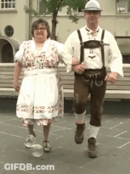 A Man And A Woman In Traditional Costume Are Dancing Together GIF