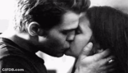 A Man And A Woman Kissing In A Black And White Photo . GIF