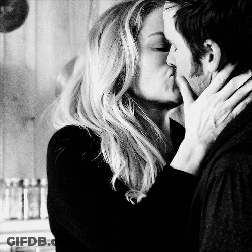 A Man And A Woman Kissing In A Black And White Photo GIF
