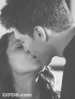 A Man And A Woman Kissing In A Black And White Photo . GIF