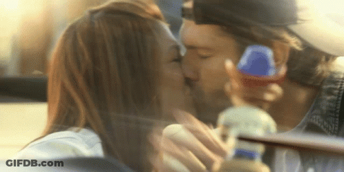 A Man And A Woman Kissing In A Car With A Bottle In The Background GIF