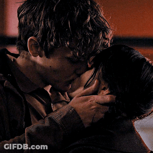 A Man And A Woman Kissing In A Dark Room GIF
