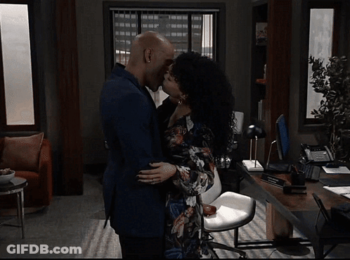 A Man And A Woman Kissing In A Living Room GIF