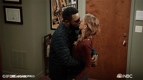 A Man And A Woman Kissing In Front Of A Door With #Chicagomed Written On The Bottom GIF