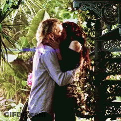 A Man And A Woman Kissing In Front Of A Staircase GIF