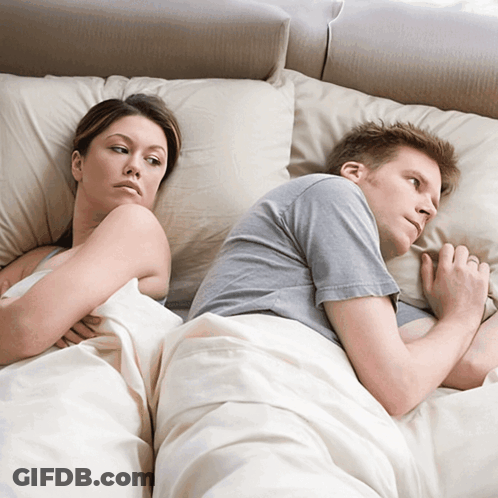 A Man And A Woman Laying Back To Back On A Bed GIF
